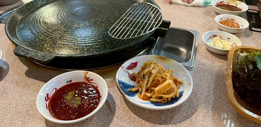 韓国江南にあるサムギョプサルのお店のサムギョプサルと副菜、にんにくなど。