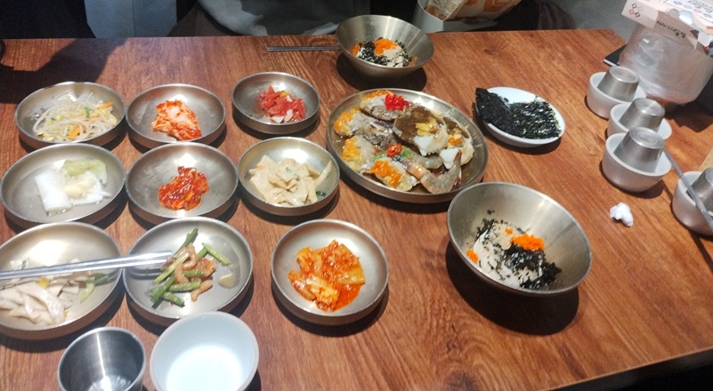韓国ソウルの街にあるカンジャンケジャンの専門店。オダリチブ・サボイホテル店のカンジャンケジャンのコース料理。机の上には副菜も並ぶ。